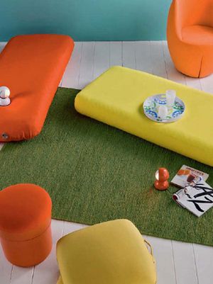 立体塑形设计的布艺座椅，以今年大热的三文鱼红和鲜柠黄色，带出了随意的潮流感。草绿色地毯中和了艳色的表现，制造出清凉感