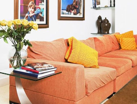 橙色的三人座沙发，搭配亮黄色的靠垫，并以大面积的白色空间作为背景，使沙发外观显得格外轻巧，空间整体的色彩搭配既张扬又有亲和力
